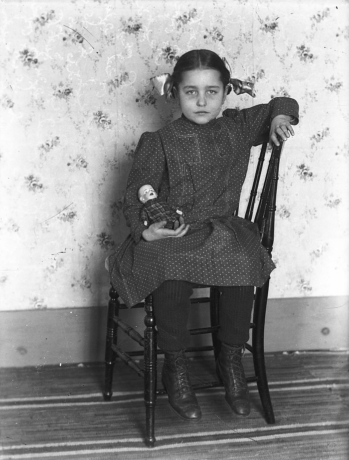 Girl holding doll, c.1900