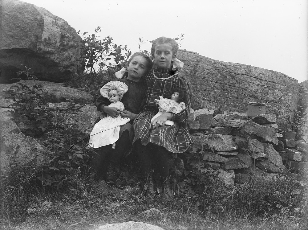 Two girls holding dolls, c.1900